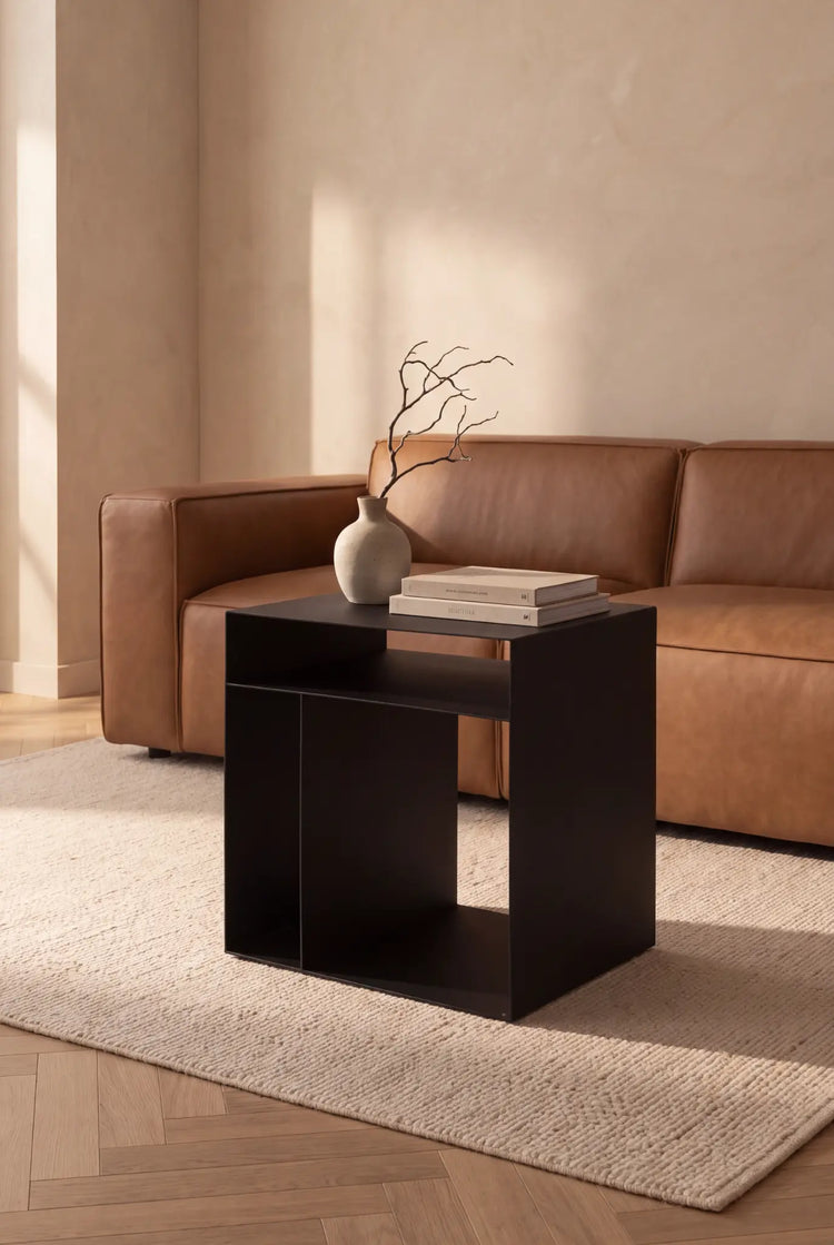 CUBO Wohnwürfel aus schwarzem Stahl mit offenem Stauraum vor einem Sofa