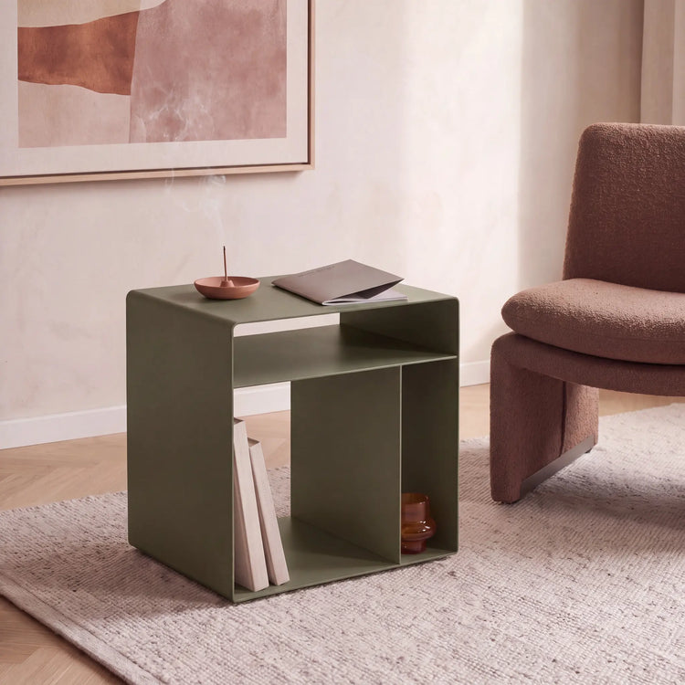 CUBO Wohnwürfel aus olivgrünem pulverbeschichtetem Stahl neben einem Sessel